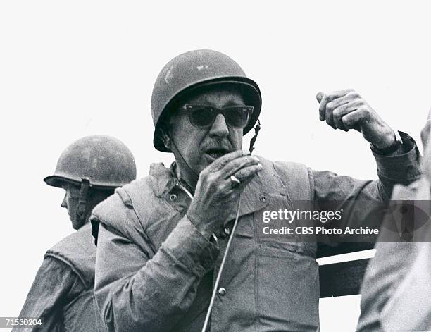 American broadcast journalist Walter Cronkite, dressed in fatigues and a helmet, speaks into a microphone during coverage of the Vietnam War,...