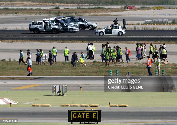 Iberia ground staff walk away under the eyes of the police after blocking the runway at Barcelona's El Prat airport, 28 July 2006. All flights to and...