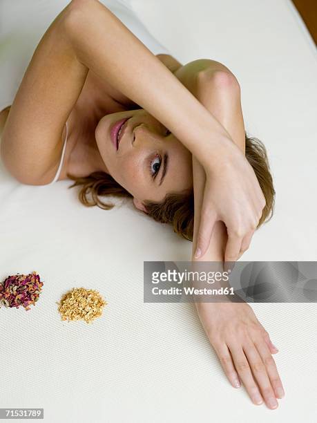 young woman lying on bed with spice, elevated view - ayurveda stock-fotos und bilder
