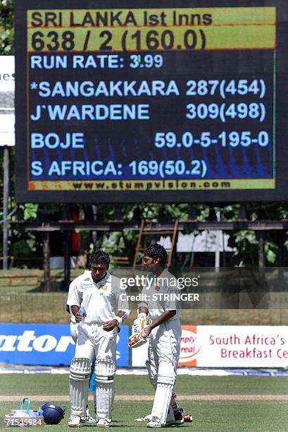 Sri Lankan cricketer Kumar Sangakkara and Sri Lankan cricket captain Mahela Jayawardene stand in front of a digital score screen during the third day...