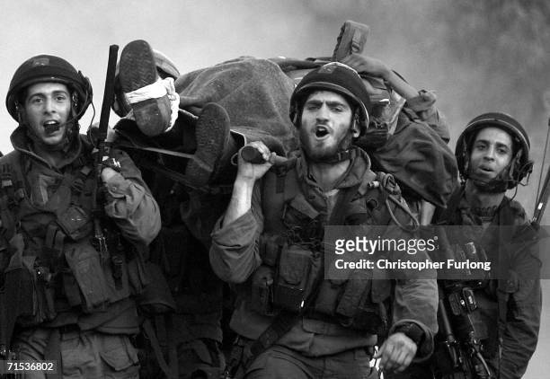 Israeli Paratroopers sing as they return at dawn carrying an injured comrade to Israel from Lebanon after seven days of fierce fighting with...
