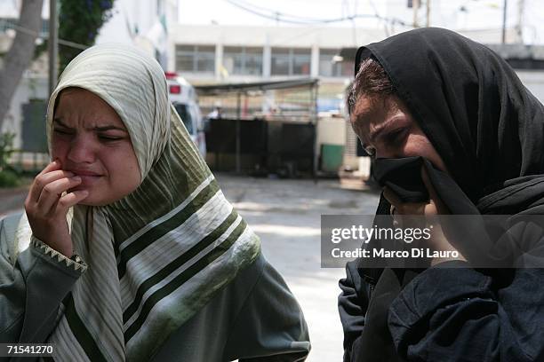 Two Lebanese woman look on at rescue teams wrapping bodies of the victims of the Qana's Israeli air strike in plastic at the morgue July 30, 2006 in...