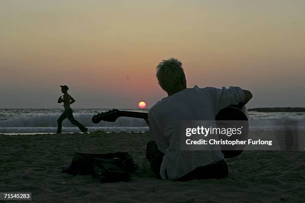 An Israeli man play his guitar on the main beach of Tel Aviv as fighting and rocket attacks continue on the north border and in southern Lebanon July...