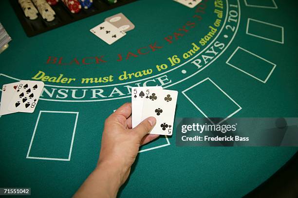 a person holding a pair of cards at a blackjack table - black jack hand stock-fotos und bilder