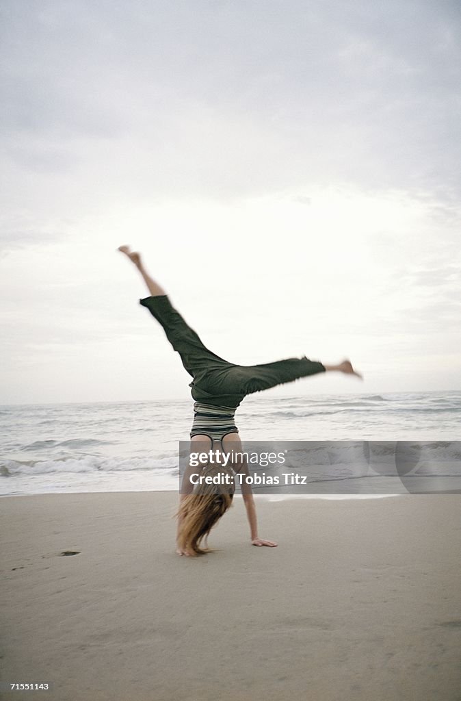 Young woman doing cartwheel on beach