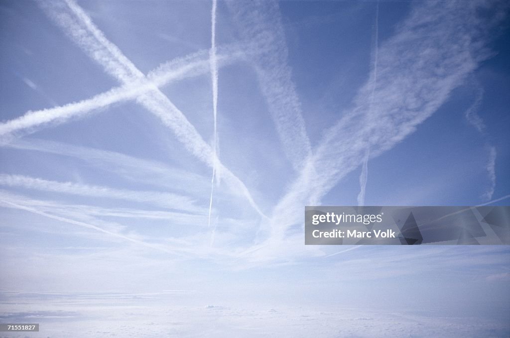 Vapor trails crossing blue sky