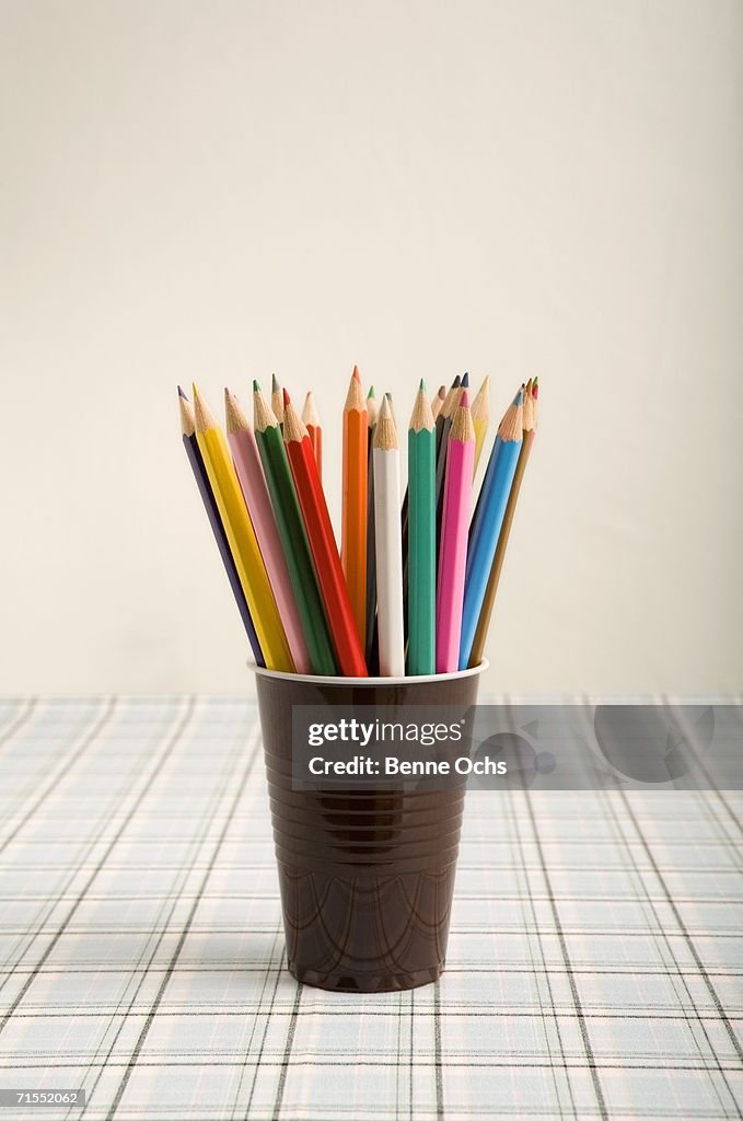 Assorted colored pencils in a plastic cup