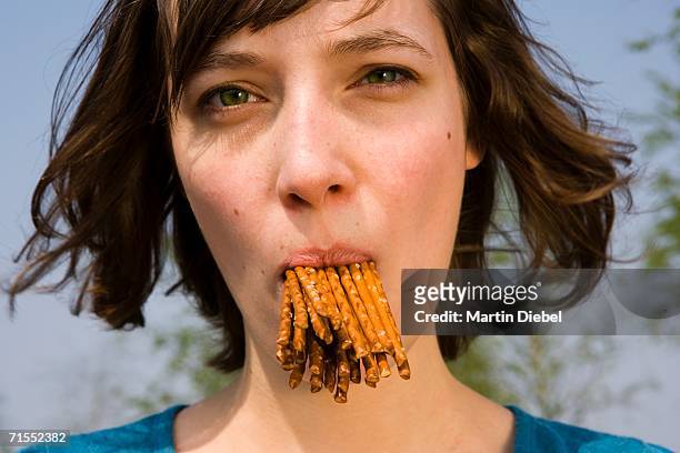 young woman with mouth full of pretzels - rempli photos et images de collection