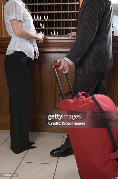 young woman and man with luggage standing at reception desk in hotel - pigeon hole stock pictures, royalty-free photos & images