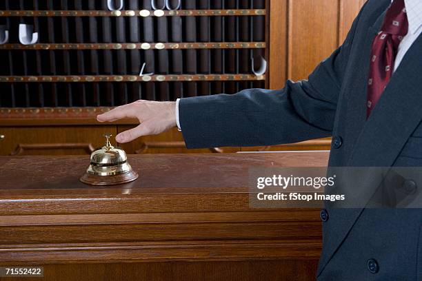 man reaching for service bell on desk at hotel reception - pigeon hole stock pictures, royalty-free photos & images