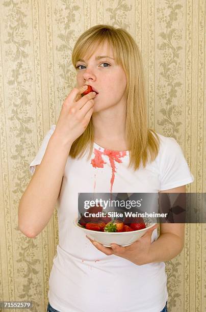 young woman eating strawberry and spilling juice on t-shirt - white shirt stain stock pictures, royalty-free photos & images