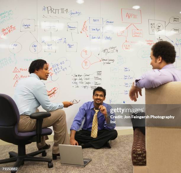 businesspeople having a meeting in front of a whiteboard wall - esigere foto e immagini stock