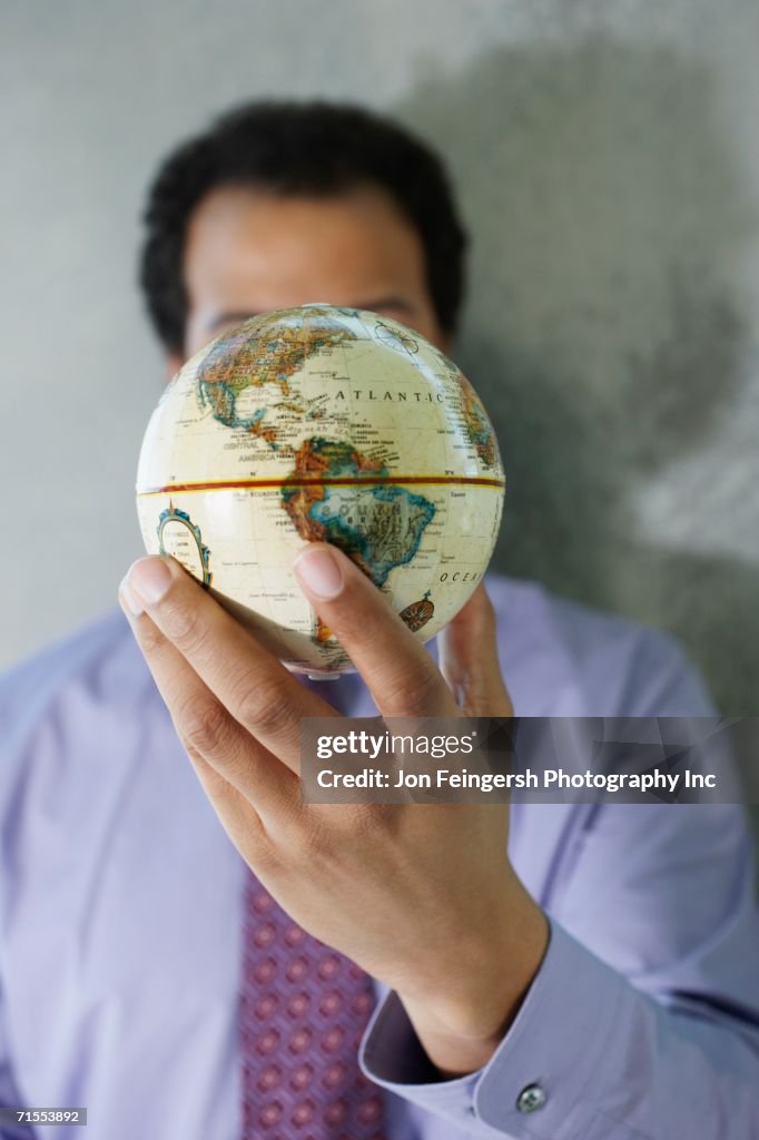 African American businessman holding globe in front of face