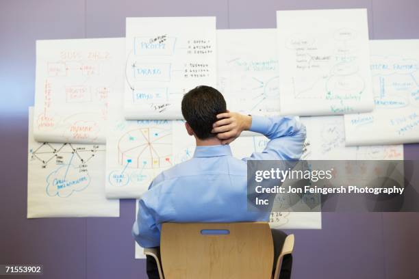 businessman looking at wall charts - esigere foto e immagini stock