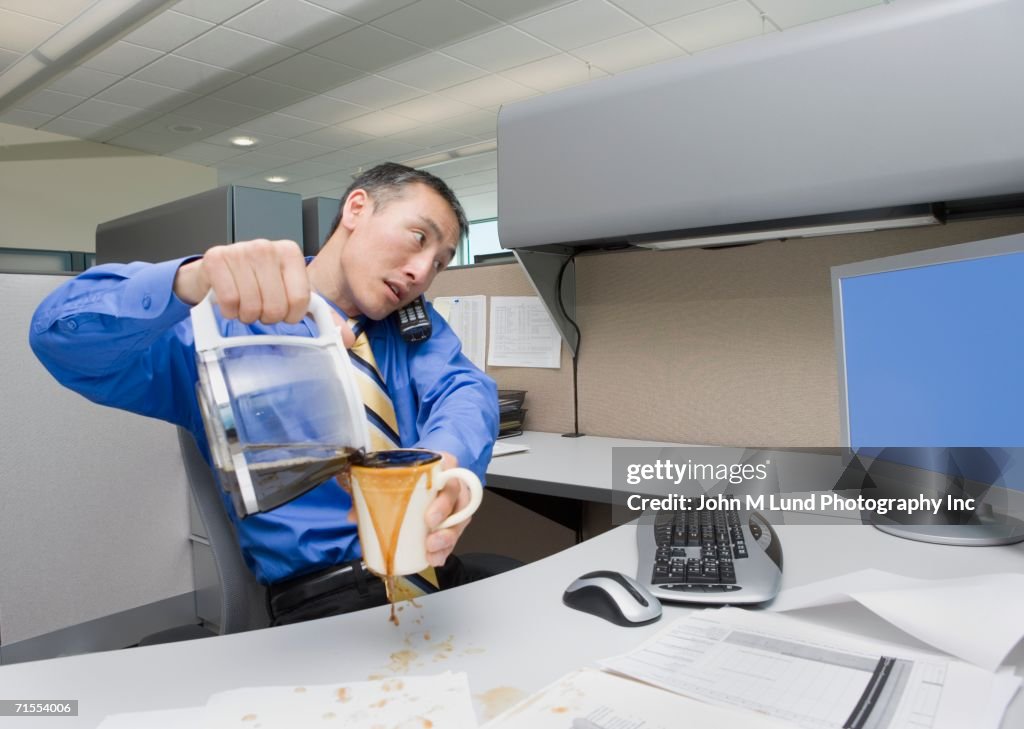 Asian businessman spilling coffee on desk