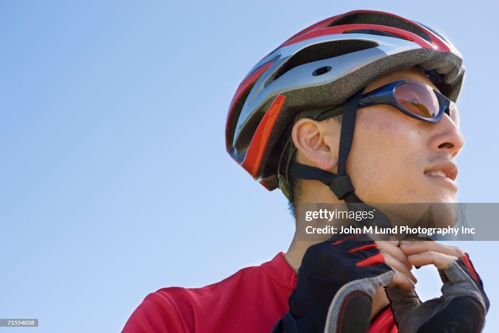 Asian man fastening bicycle helmet