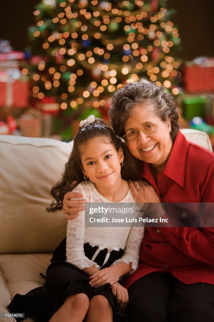 Hispanic grandmother and granddaughter in front of Christmas tree