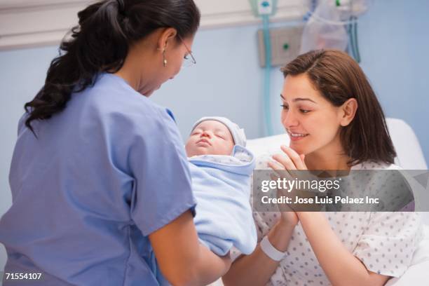 female nurse handing newborn baby to mother - mexican and white baby stock pictures, royalty-free photos & images