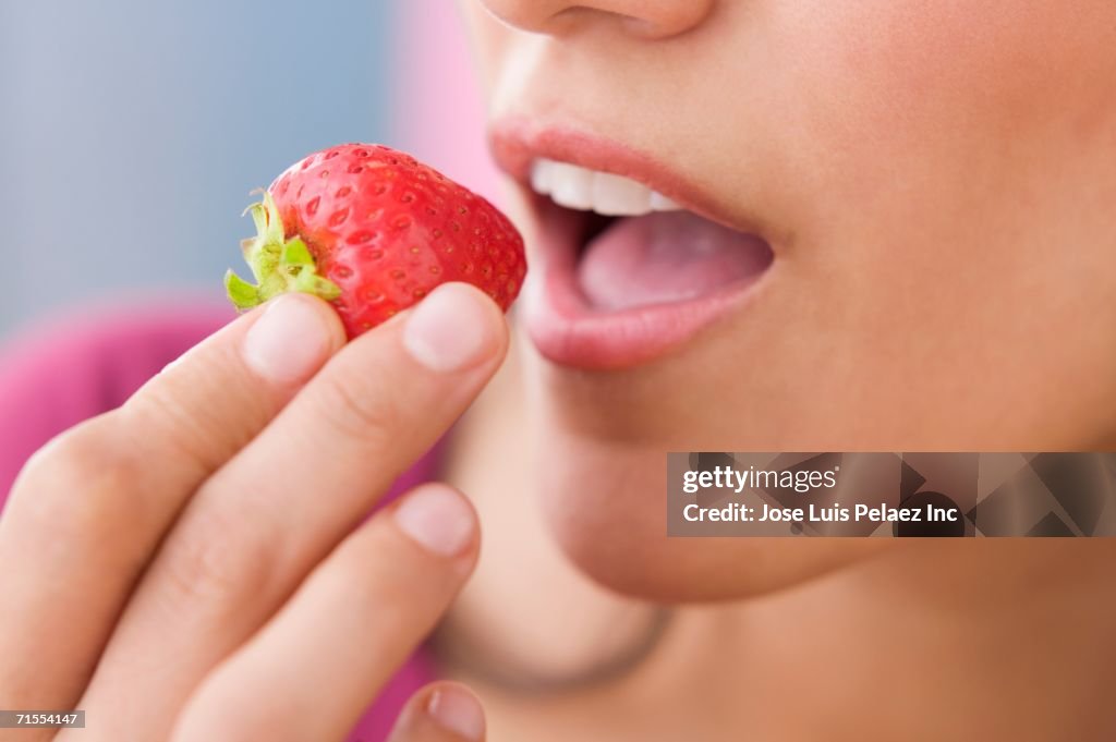 Close up of Hispanic woman eating strawberry