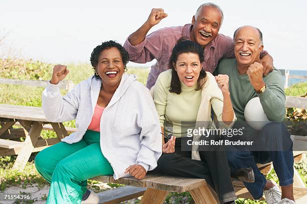 two senior couples cheering outdoors - garden table stock-fotos und bilder