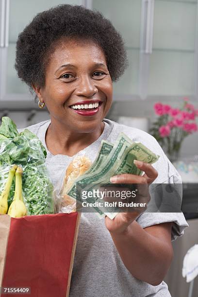 senior african american woman with money and groceries - african american woman with money stock-fotos und bilder