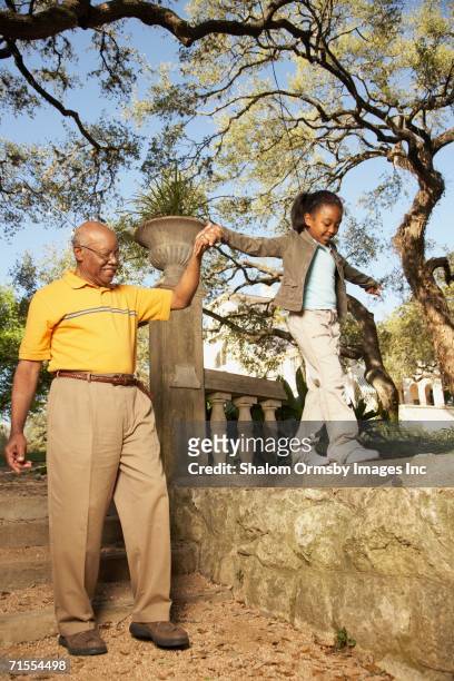 african american grandfather walking with granddaughter - ages 65 70 stockfoto's en -beelden