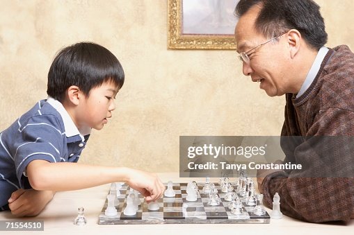 Asian father and young son playing chess Asian father and young son playing chess