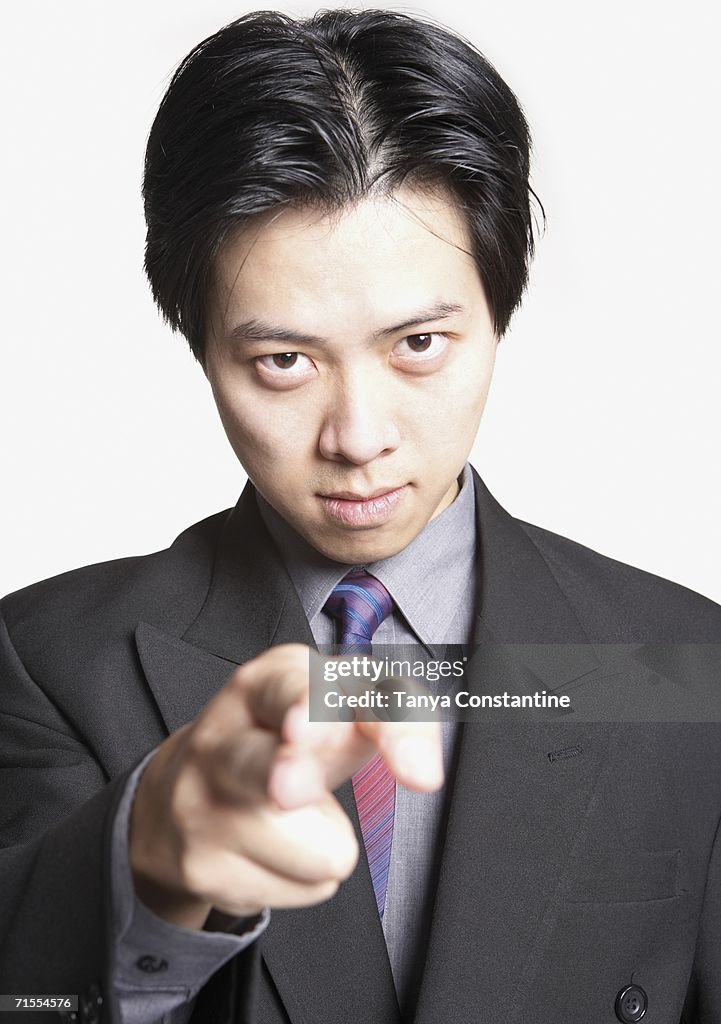 Studio shot of Asian businessman pointing finger