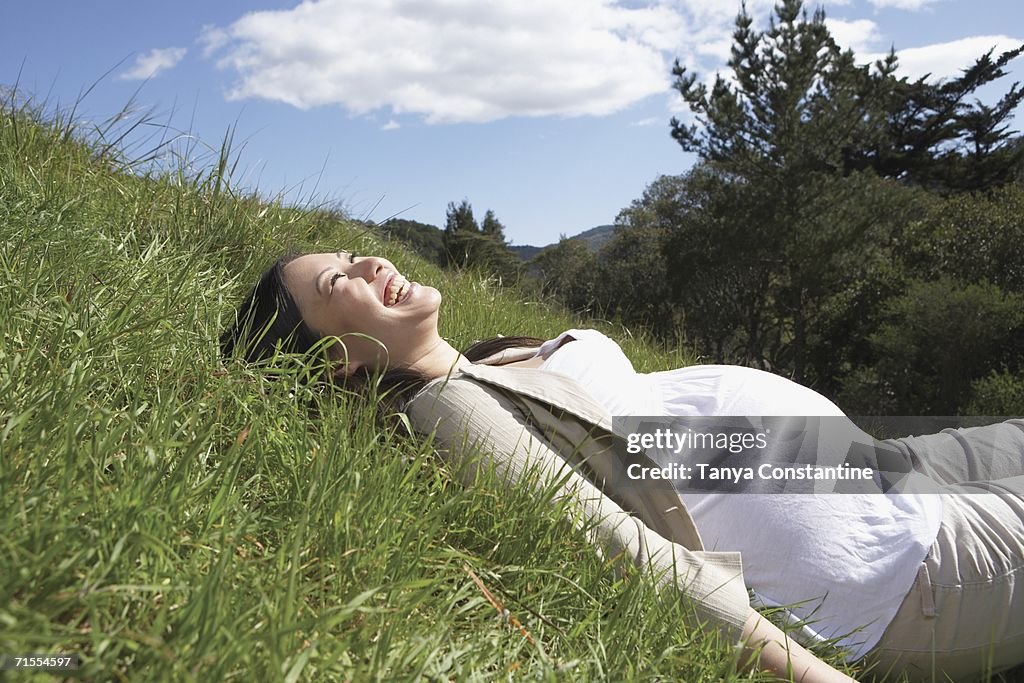 Pregnant Asian woman laying in the grass