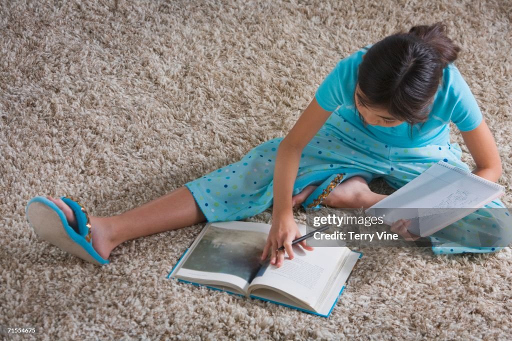 Young Hispanic girl doing homework on the floor