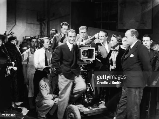 English actor Robert Douglas stands on a camera dolly at the opening of Pinewood Studios in Buckinghamshire, 30th September 1936. With him are...