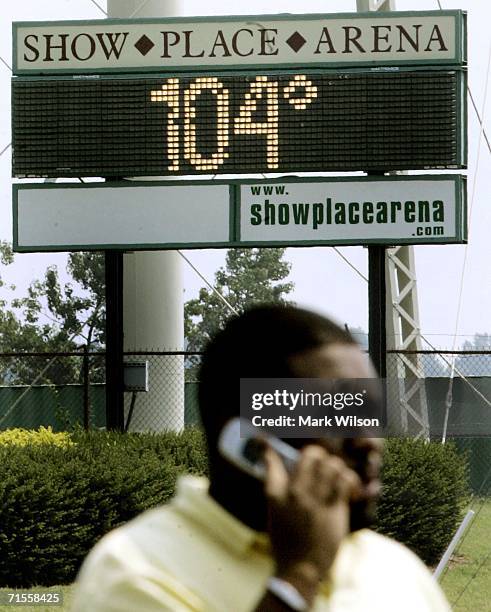Man talks on his cell phone while a bill board temperature sign reads 104 degrees at the Show Place Arena and Prince George's Equestrian Center...