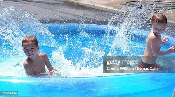 Alberto Barreto and James Barreto, 4 are splashed in a pool by Steven Tonkin, who is under water during a heat wave gripping the northeast August 1,...