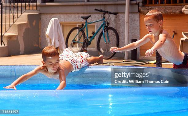 Alberto Barreto 6, and James Barreto, 4 dive into a pool during a heat wave gripping the northeast August 1, 2006 in Philadelphia, Pennsylvania....