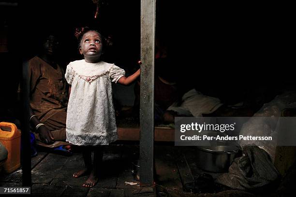 Mama Songo, age 2.5, a daughter of a crew member, looks at her mother after taking a bath under the deck while traveling on a boat made of big trees...