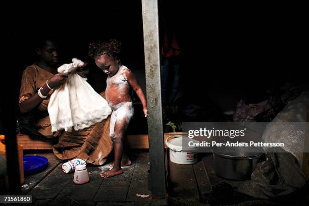 Mama Songo, age 2.5, a daughter of a crew member, gets dressed after taking a bath under the deck, while traveling on a boat made of big trees on the...