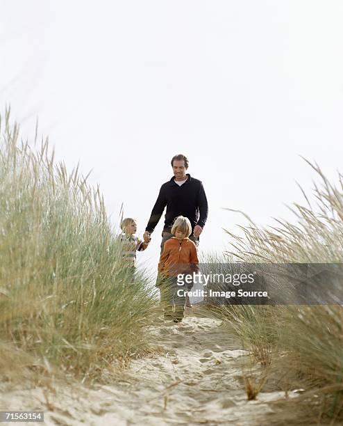 family walking down a dune - marram grass stockfoto's en -beelden