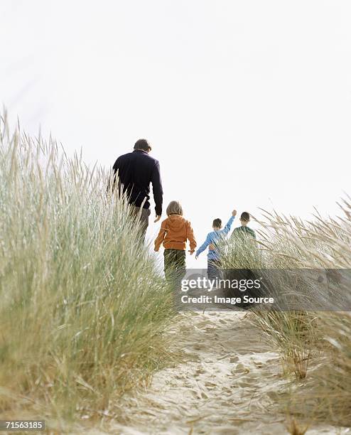 family walking down a dune - marram grass stock pictures, royalty-free photos & images