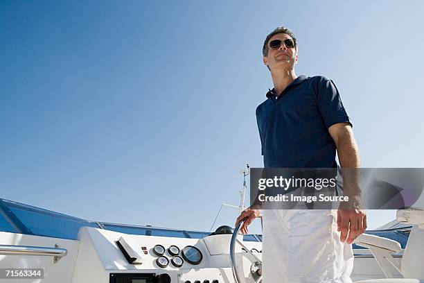 man steering a yacht - high end fashion stock pictures, royalty-free photos & images