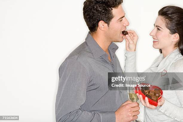 woman feeding chocolates to boyfriend - sharing chocolate stock pictures, royalty-free photos & images