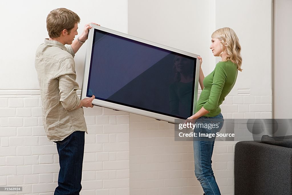Couple transportant téléviseur à écran plasma