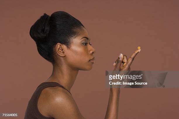young woman holding a capsule - black woman beauty treatment stock pictures, royalty-free photos & images