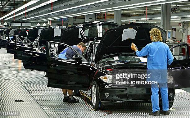 Picture taken 01 July 2004 shows employees of German luxury carmaker BMW working at a company's factory building in Regensburg, southern Germany. BMW...