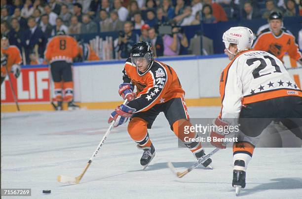 Mats Naslund of the Wales Conference and the Montreal Canadiens skates with the puck as he is defended by Gary Suter of the Campbell Conference and...
