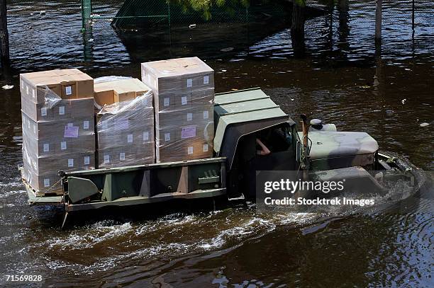 "a national guard m817 5-ton dump truck fords the floodwaters left by hurricane katrina to take supplies to the super dome in downtown new orleans, louisiana (la). " - hurricane katrina relief stock pictures, royalty-free photos & images