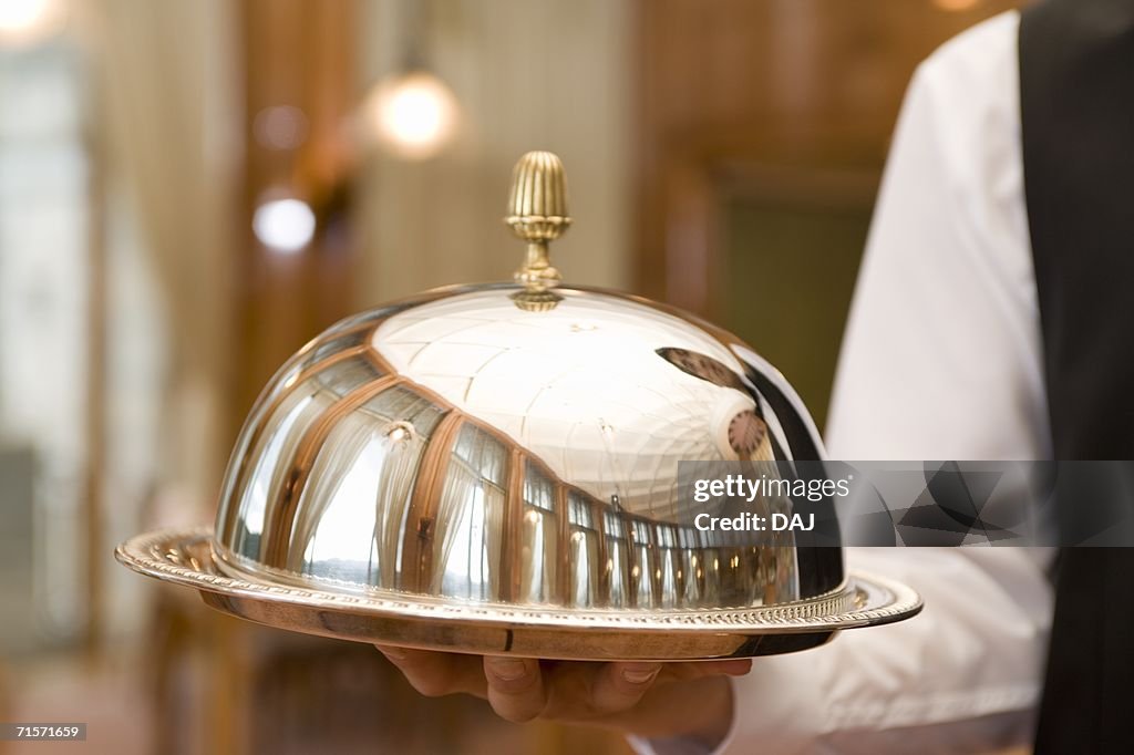 Young waiter carrying tray, front view