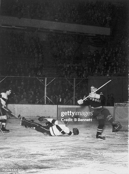 Canadian professional hockey player Bill Durnan , goaltender for the Montreal Canadiens, falls on the ice as he attempts to block a play by New York...