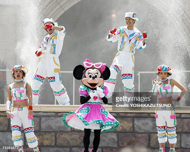 Disney character Minnie Mouse and dancers perform as water splashes up outside Cinderella's castle to cool down the guests during the new summer...