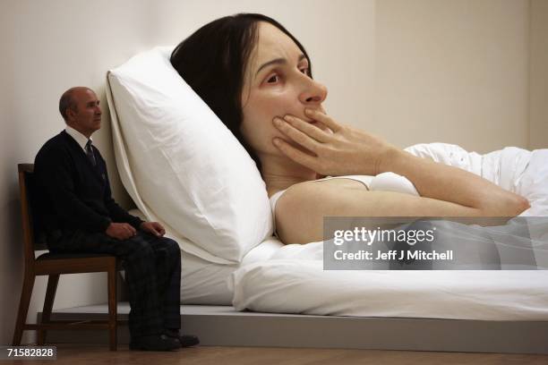 Man sits next to the work of Australian born, London-based sculptor Ron Mueck at the National Galleries of Scotland on August 4, 2006 Edinburgh in...