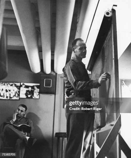 American football player and coach Tom Landry of the New York Giants writes on a chalk board in the locker room at Yankee Standium, New York, New...